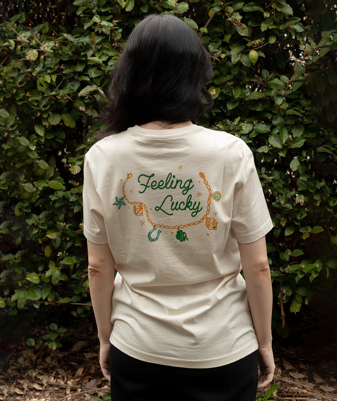 Back view of the Feeling Lucky Tee SS featuring a playful design on a cream shirt.