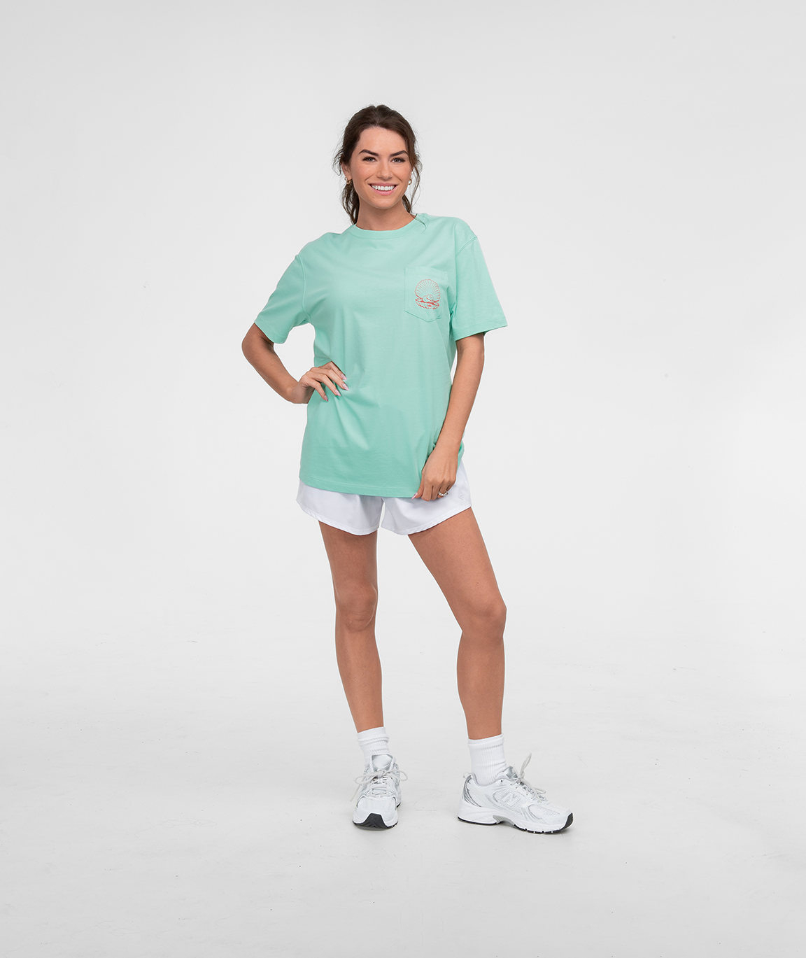 Model wearing the Wave Wrangler Tee SS in mint color, paired with shorts and sneakers, showcasing a casual look.