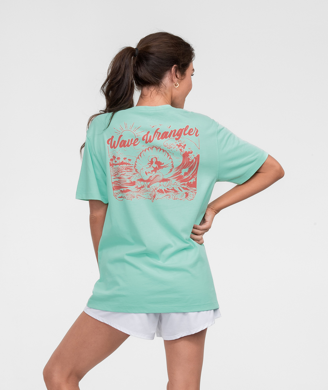 Woman wearing a mint green Wave Wrangler Tee SS with a vibrant back design.